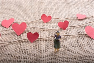 Woman figurine and Love concept with paper heart on threads