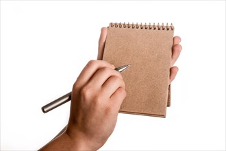 Spiral brown notebook and a pen in child hand on a white background