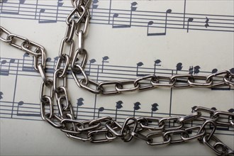 Metal chain placed on a paper with musical notes