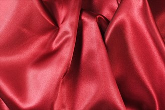 Shiny red satin textile texture with folds