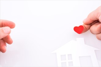 Paper house and heart shape in hand on a white background