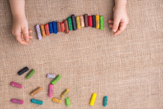 Toddlers hand putting crayons in line on canvas