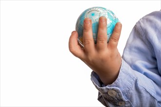 Baby with blue shirt holding a small globe in hand on white background