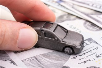 Model car in hand placed US dollar banknotes spread on ground