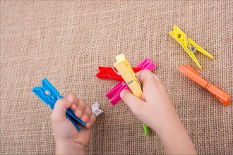 Color clothespin in hand on a linen canvas background