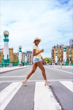 Portrait of black ethnic woman having an orange juice enjoying summer on vacation crossing the street