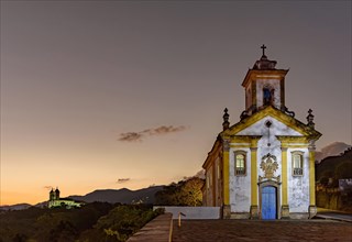 Image with illuminated baroque style churches on top of the hill in Ouro Preto
