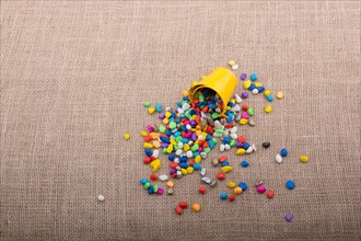 Bucket of colorful pebbles spill on background