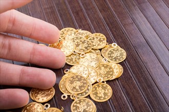 Plenty of fake gold coins in hand on wooden background