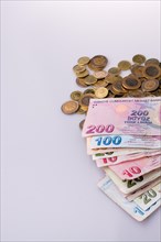 Turkish Lira coins and banknotes side by side on white background