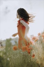 Girl in a red dress in a poppy meadow