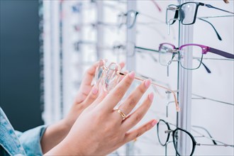 Female buyer choosing glasses in a store. Female customer choosing glasses in an optical store