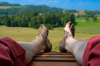Feet of a man on a wooden lounger at the Wuppenau barefoot path on the Nollen