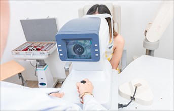 Optometrist using refractometer with patient. Eyesight of a patient on the screen of the refractometer