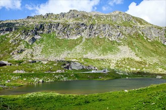 View of small lake with parking space for motorhomes behind historic Hotel Hospiz at Gotthard Pass