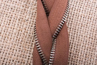 Parts of the brown color zipper on linen canvas background