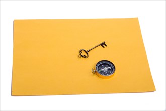 Key and compass on a sheet of colored plain paper with a white background