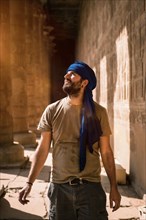 A young tourist in a blue turban visiting the Edfu Temple in the morning near Aswan city. Egypt