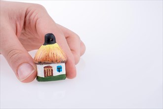 Hand holding a small traditional hut on a white background