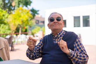 An elderly man dancing in the garden of a nursing home or retirement home at a summer party wearing sunglasses
