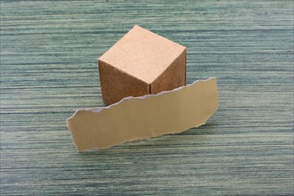Torn paper and a paper box cube on wooden texture