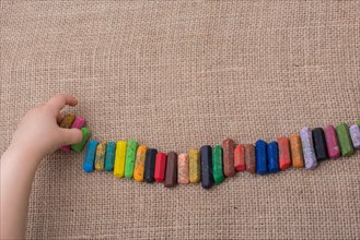 Toddlers hand putting crayons in line on canvas