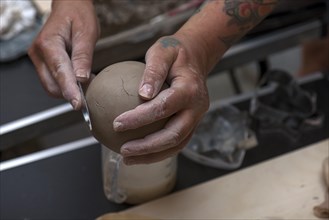 Potter's hands forming a clay ball