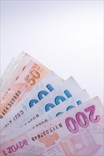Turkish Lira banknotes by the side of a model house on white background