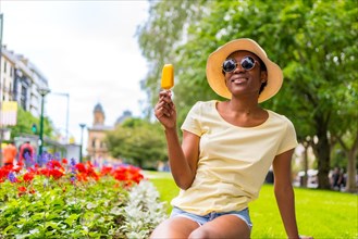 African black ethnicity woman eating a mango ice cream in the city