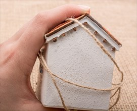 Thread wrapped around a model house on a brown background