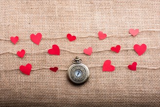 Love concept with pocket watch and paper hearts on threads