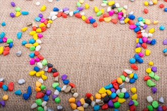 Colorful little pebbles form a heart shape on canvas ground