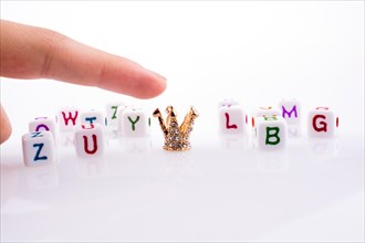 Hand pointing at Crown between Letter cubes on a white background