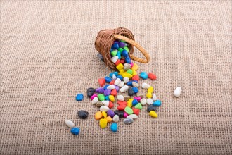 Basket of colorful pebbles spill on background