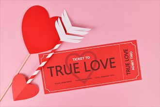Cute Valentine's day concept with 'True Love' ticket and cupid arrow on pink background