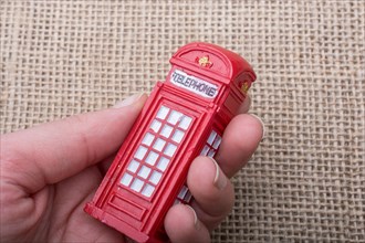 Hand holding a phone booth on a linen canvas background
