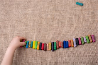 Toddlers hand putting crayons in line on canvas