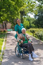 Portrait of an elderly woman with the nurse on a walk in the garden of a nursing home in a wheelchair