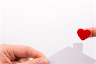 Paper house and heart shape in hand on a white background