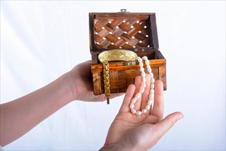 Hand holding a jewellery box with pearl necklace in it on a white background