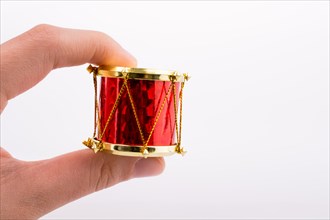 Hand holding a small drum on a white background