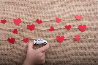 Love concept with car and paper heart on linen threads