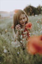 Girl in a red dress in a poppy meadow