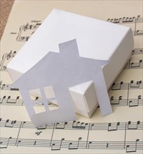 Paper house placed on a paper with musical notes