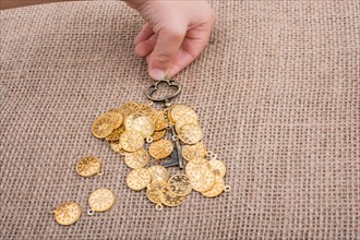 Hand holding a retro styled key over fake gold coins