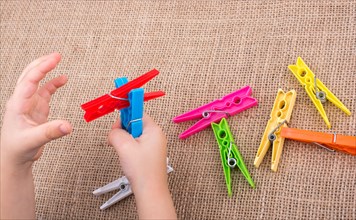 Color clothespin in hand on a linen canvas background