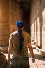Young man in blue turban walking on the columns of the Edfu Temple near the city of Aswan. Egypt