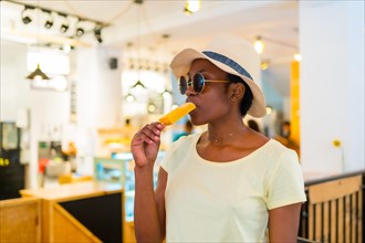 Black African ethnicity woman customer eating an ice cream in a shop