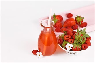 Red strawberry and raspberry fruit lemonade in jar surrounded by berries