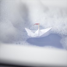 Paper ship in a bathtub with lots of foam